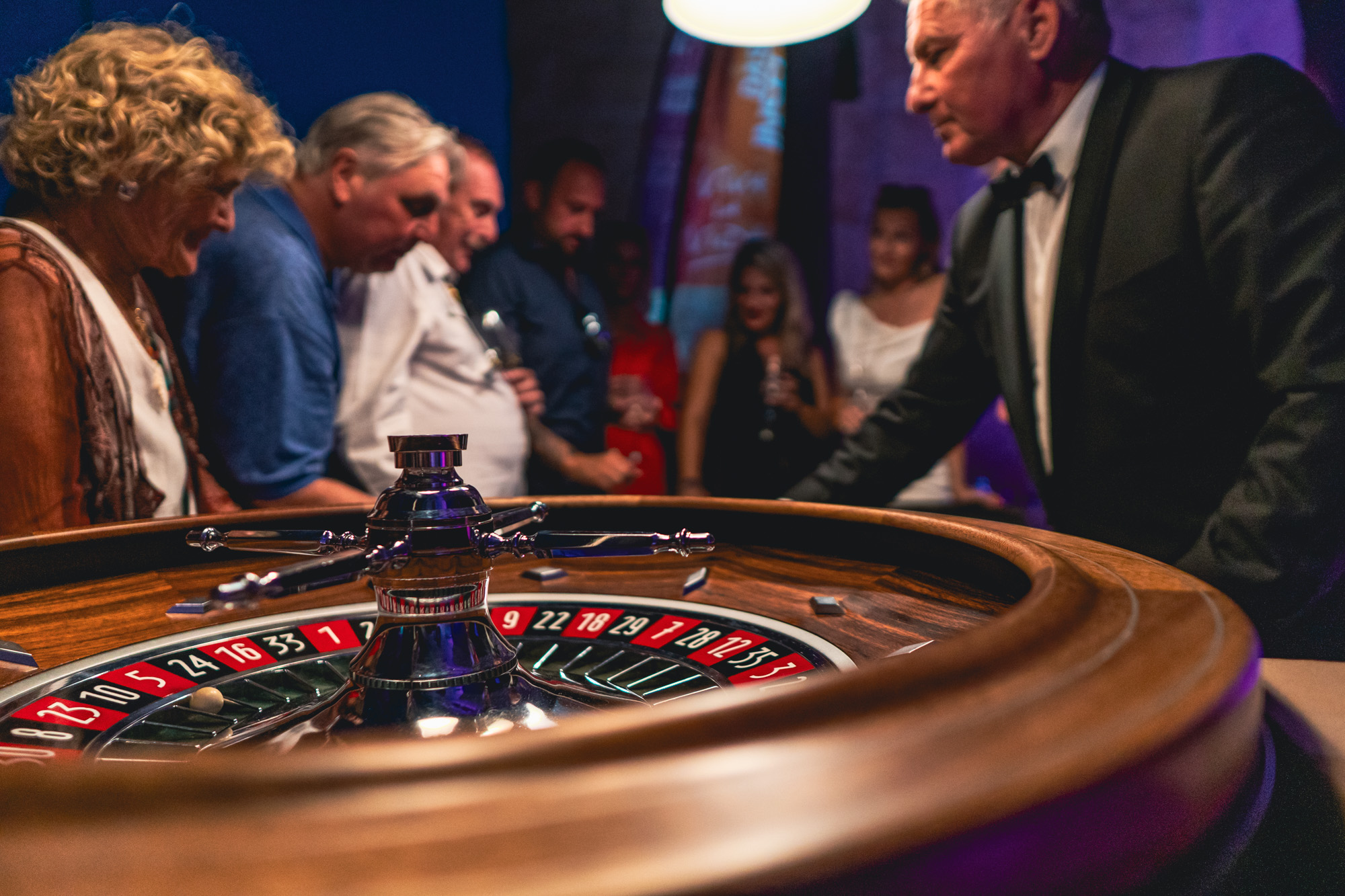 Guests gathered around a roulette table at an evening event.