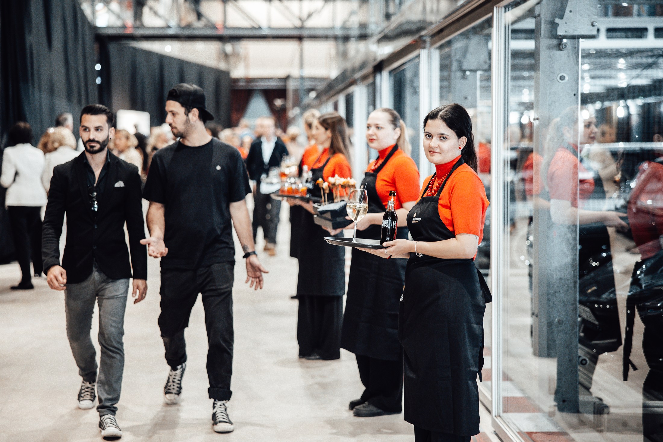 Hospitality staff carrying drinks through the Motorworld Mallorca venue.