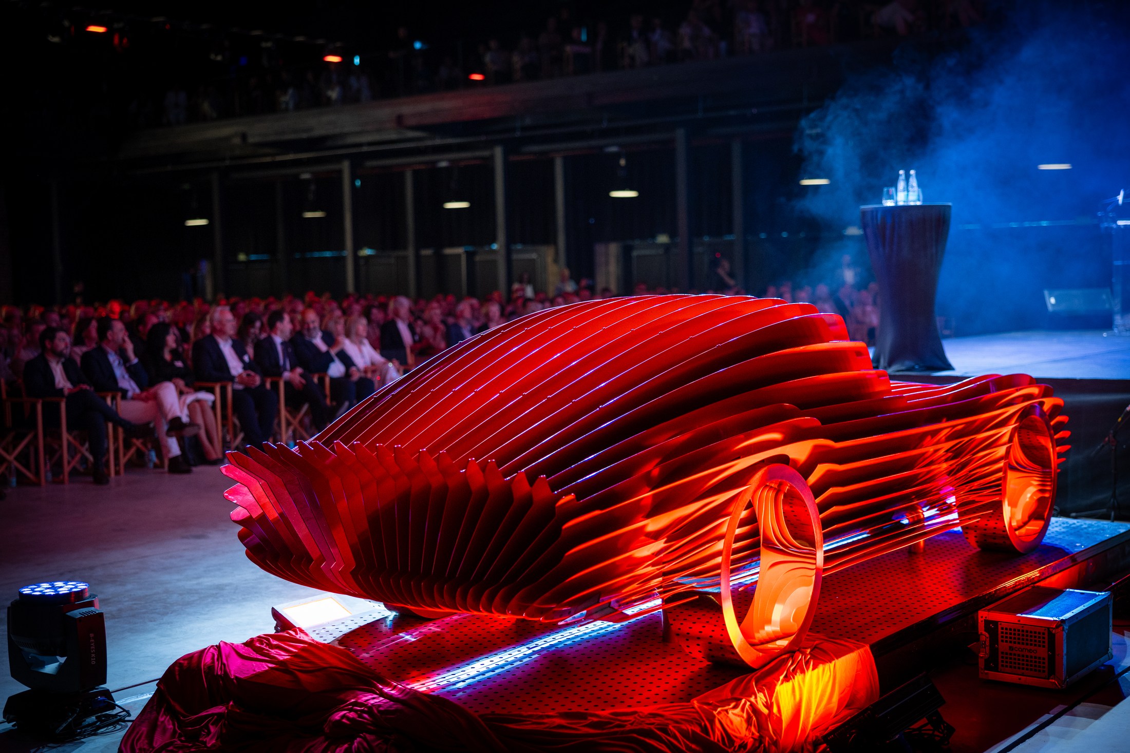 Red concept car illuminated on stage during an evening presentation.