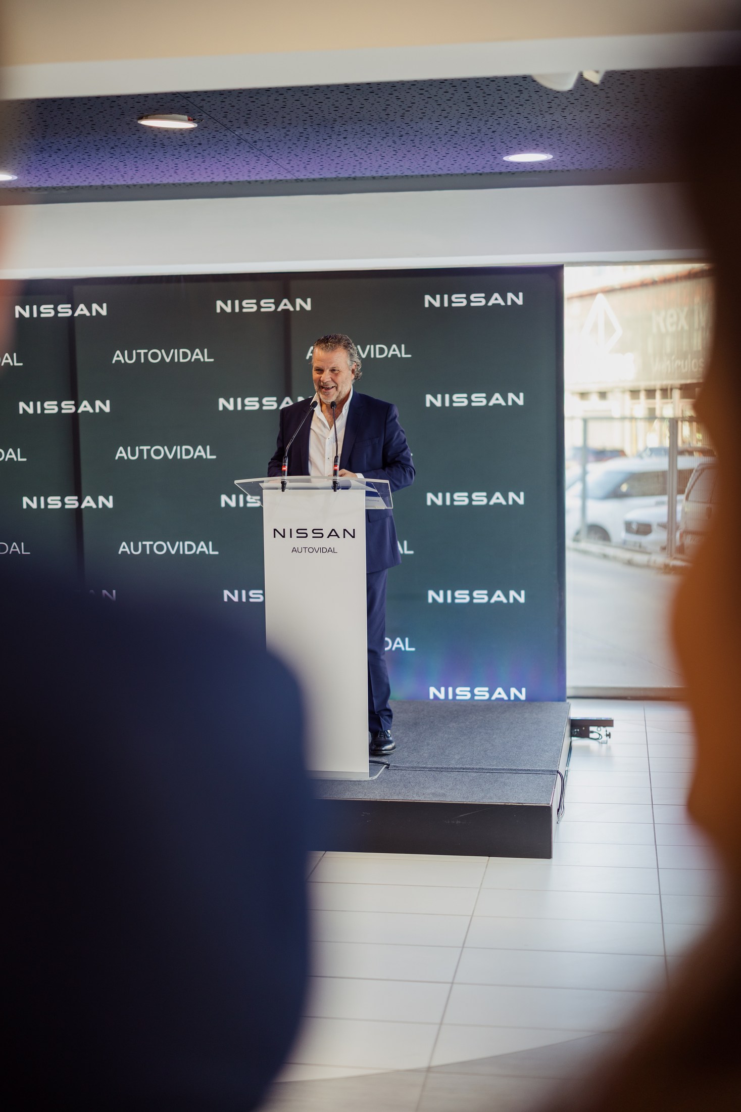 Speaker at a Nissan lectern during a corporate event.