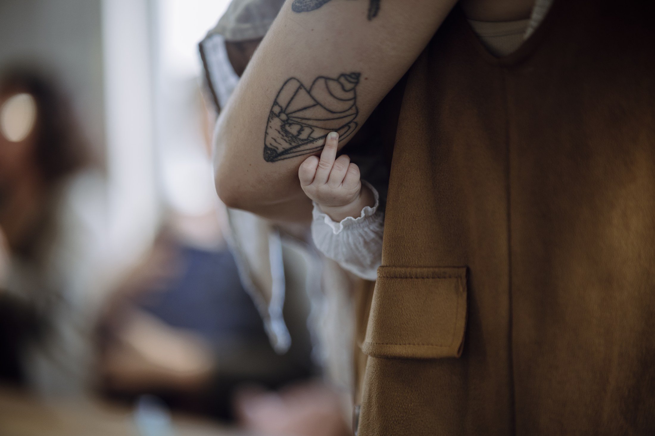 Close detail of a tattooed person fastening clothing.