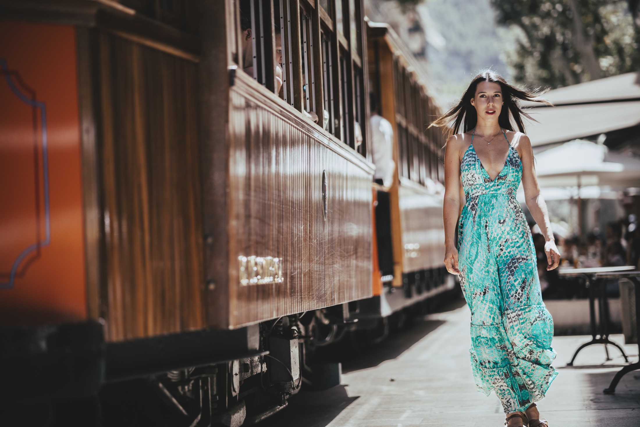 Woman in a turquoise dress walking beside a historic train.