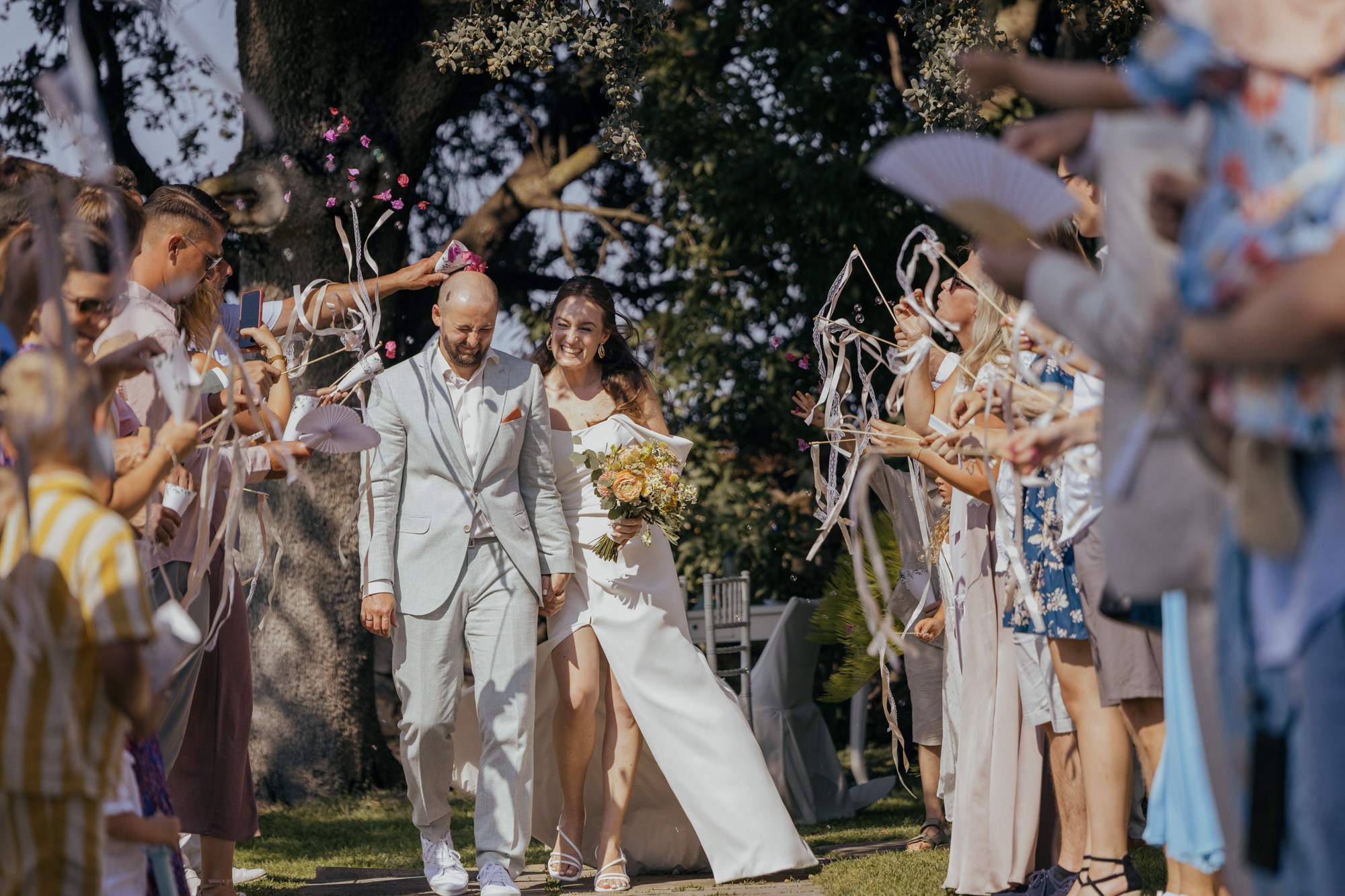 Bride and groom walking through cheering guests after the ceremony.