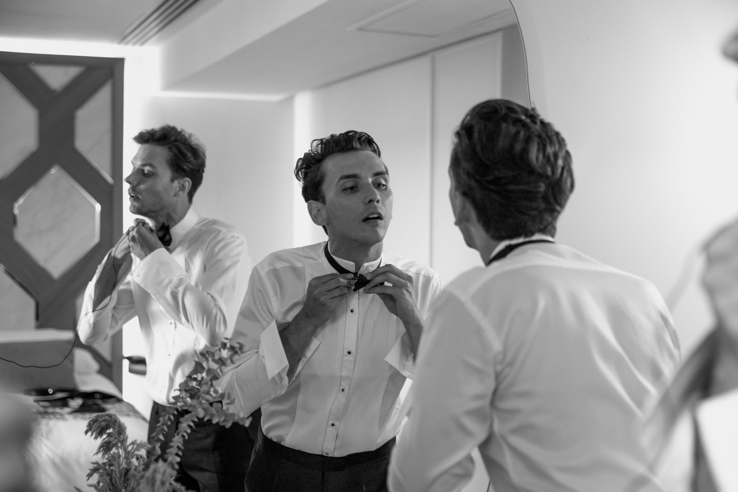 Groom getting ready with friends in a black-and-white photograph.