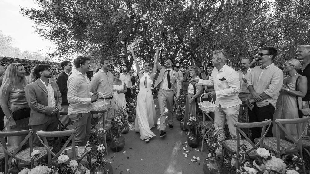 Black-and-white ceremony scene with Isabelle and Arne surrounded by guests.